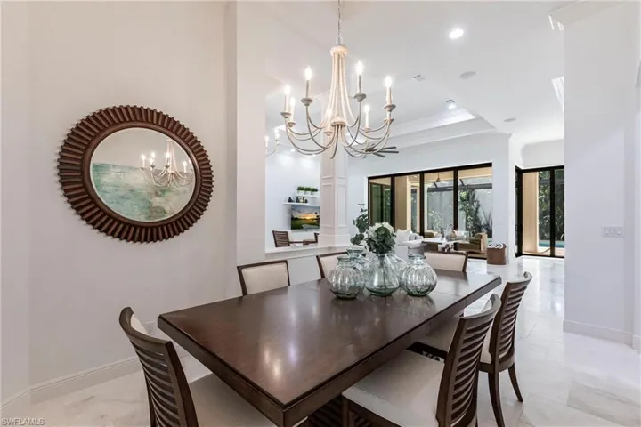 Dining space with an inviting chandelier, crown molding, baseboards, and a tray ceiling