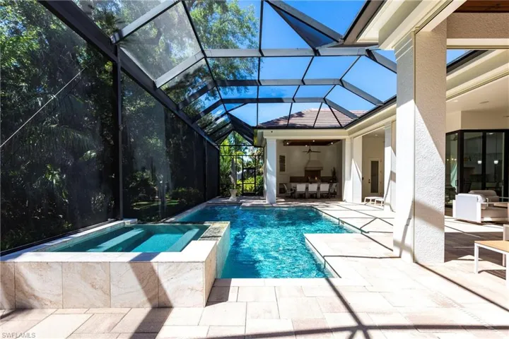 View of swimming pool with glass enclosure, a patio, and a pool with connected hot tub