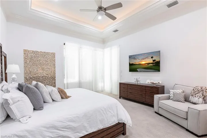 Bedroom with visible vents, light carpet, a raised ceiling, and crown molding