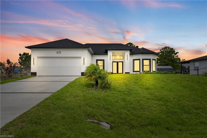 View of front facade featuring stucco siding, an attached garage, a front yard, and concrete driveway