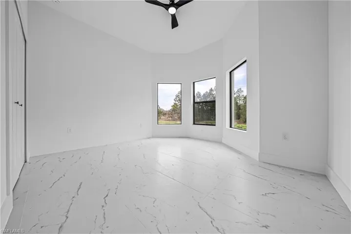 Empty room featuring ceiling fan and light marble finish floors