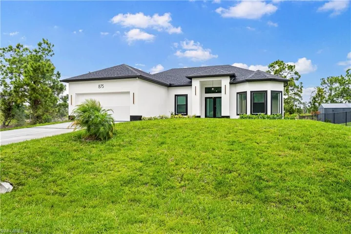 Prairie-style house with a garage, stucco siding, a front yard, and concrete driveway