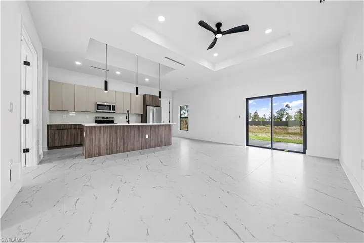Kitchen featuring open floor plan, an island with sink, light countertops, a ceiling fan, and modern cabinets