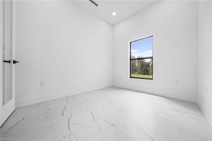 Empty room featuring recessed lighting, light marble finish floors, and a high ceiling