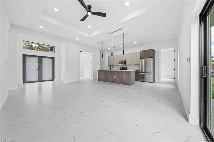 Unfurnished living room with ceiling fan, french doors, recessed lighting, and a tray ceiling