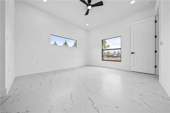 Empty room with plenty of natural light, recessed lighting, a ceiling fan, and light marble finish floors