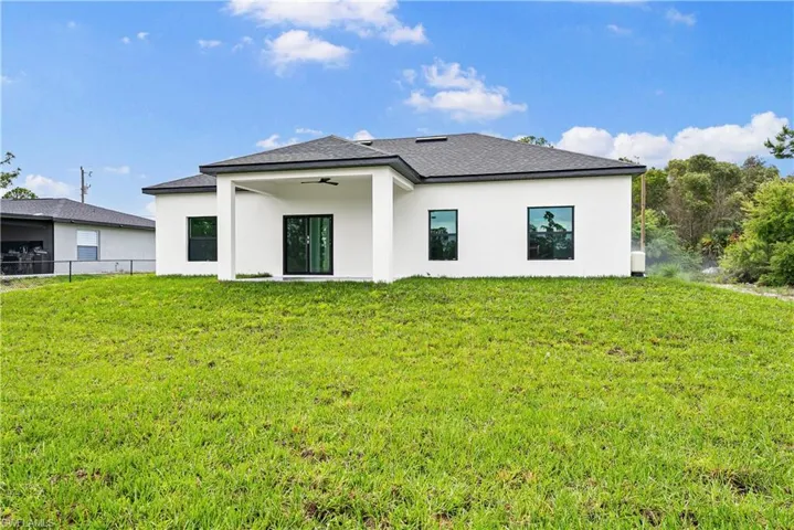 Rear view of house featuring a patio area, stucco siding, and a yard