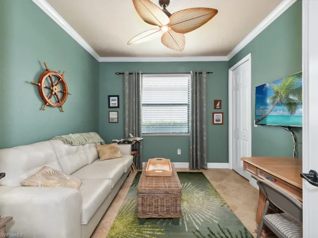 Living room featuring crown molding, baseboards, ceiling fan, and light tile patterned floors