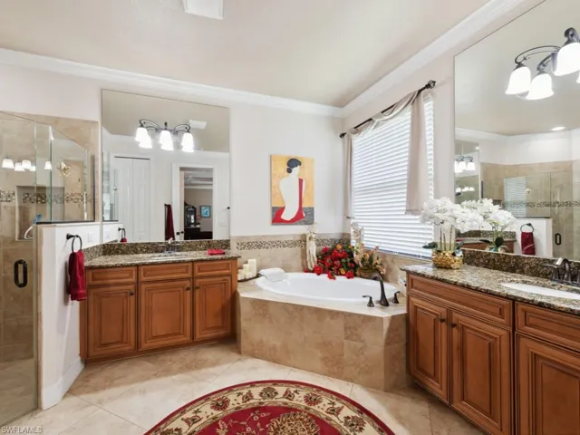 Bathroom featuring tile patterned flooring, ornamental molding, a bath, a shower stall, and a sink