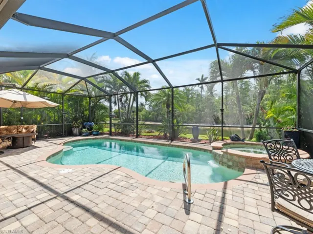 View of pool with glass enclosure, a patio area, and a pool with connected hot tub