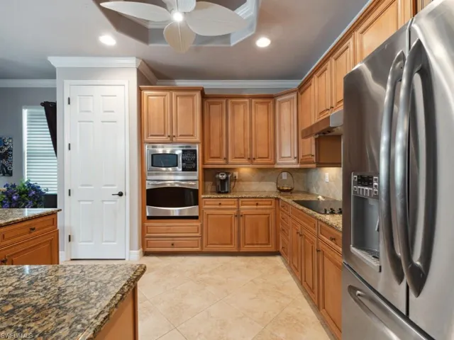 Kitchen featuring ornamental molding, ceiling fan, under cabinet range hood, backsplash, and stainless steel appliances
