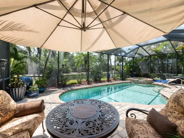 View of pool with glass enclosure, a patio area, and a pool with connected hot tub