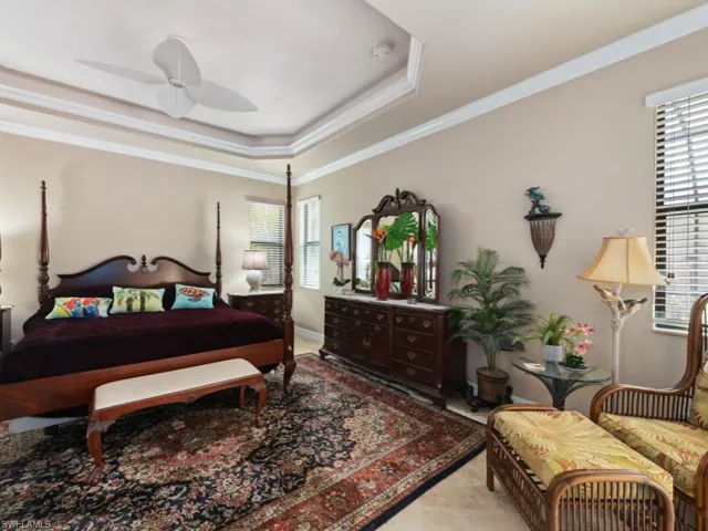 Bedroom with ceiling fan, ornamental molding, and a tray ceiling