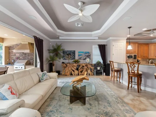 Living area with visible vents, ornamental molding, a raised ceiling, and ceiling fan