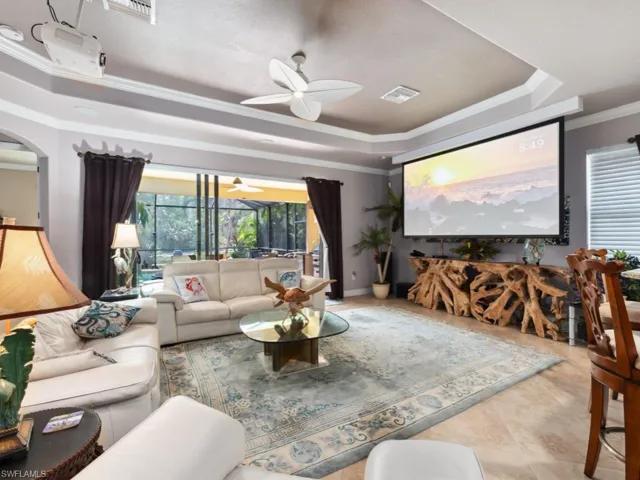 Tiled living room with ceiling fan, visible vents, ornamental molding, and a raised ceiling