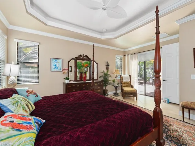 Tiled bedroom with ornamental molding, a raised ceiling, ceiling fan, and access to exterior