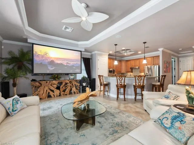 Living room featuring a ceiling fan, visible vents, and ornamental molding