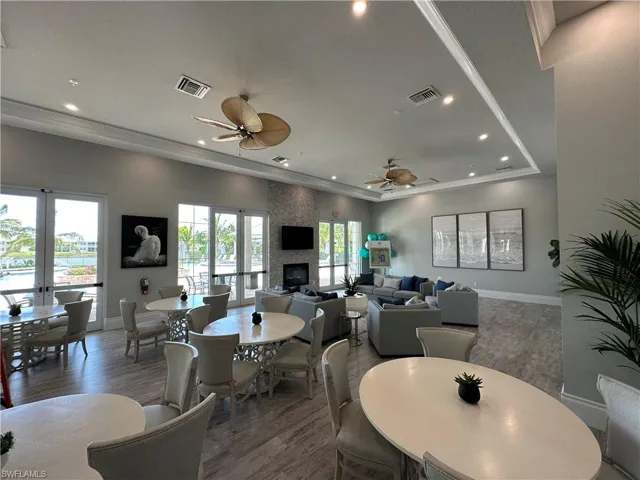 Dining room with french doors, wood finished floors, a large fireplace, recessed lighting, and a tray ceiling