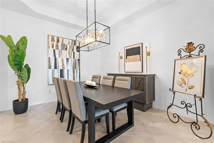Dining area with a notable chandelier, a raised ceiling, and light tile floors