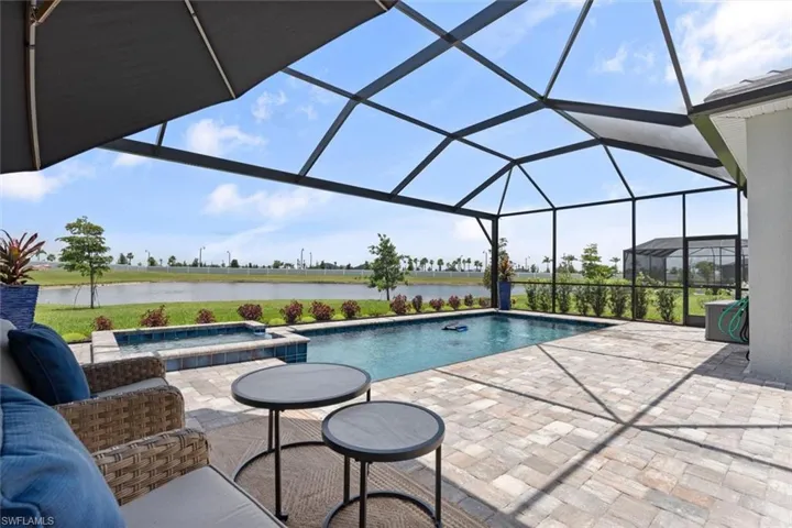 View of pool with a patio, a water view, and an in ground hot tub