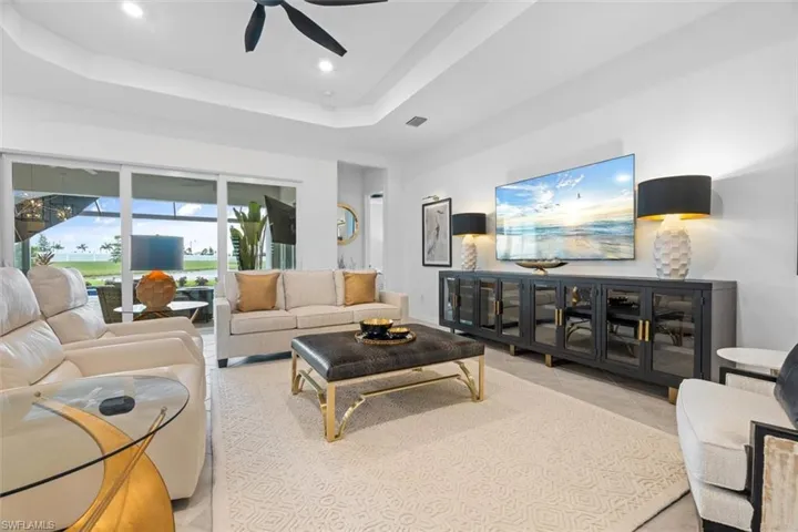 Living room featuring tile floors, ceiling fan, and a raised ceiling