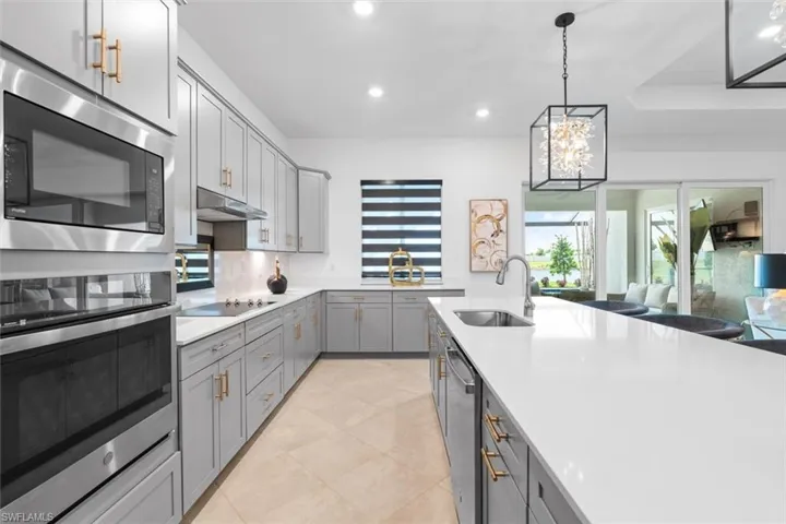 Kitchen featuring light tile flooring, gray cabinets, hanging light fixtures, sink, and appliances with stainless steel finishes