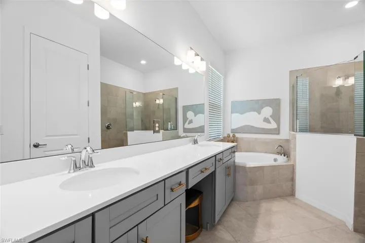 Bathroom with dual bowl vanity, tile flooring, and independent shower and bath