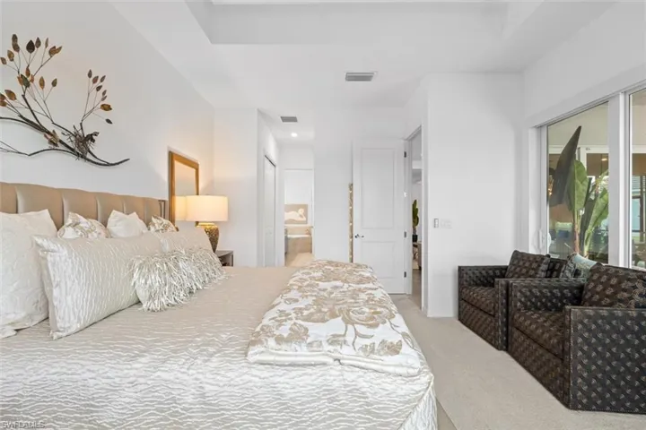 Bedroom with a raised ceiling, ensuite bath, and carpet floors
