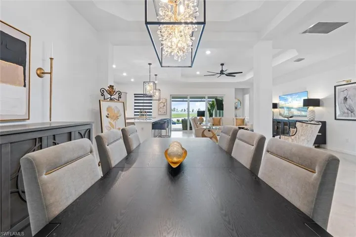 Dining area featuring wood-type flooring, a tray ceiling, and ceiling fan with notable chandelier
