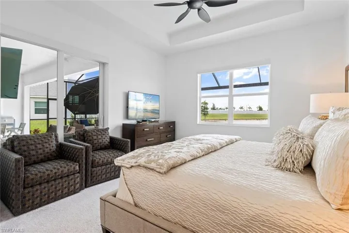 Bedroom with a raised ceiling, access to exterior, ceiling fan, and carpet floors