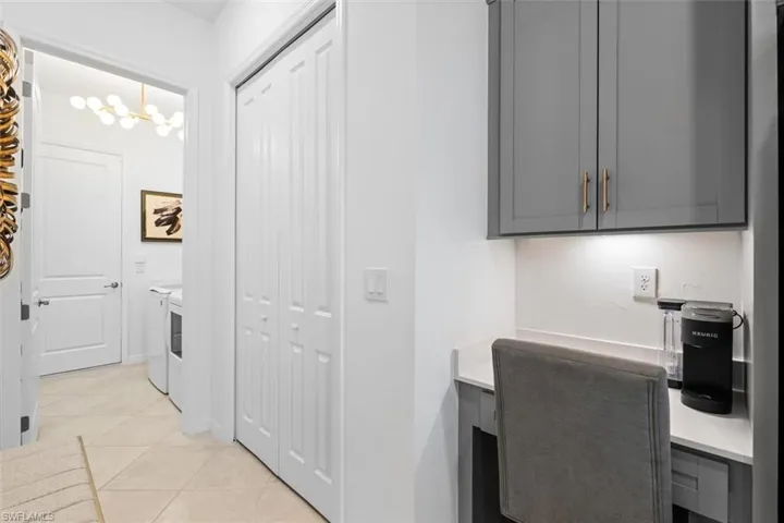 Office area with a notable chandelier, washer and clothes dryer, and light tile floors