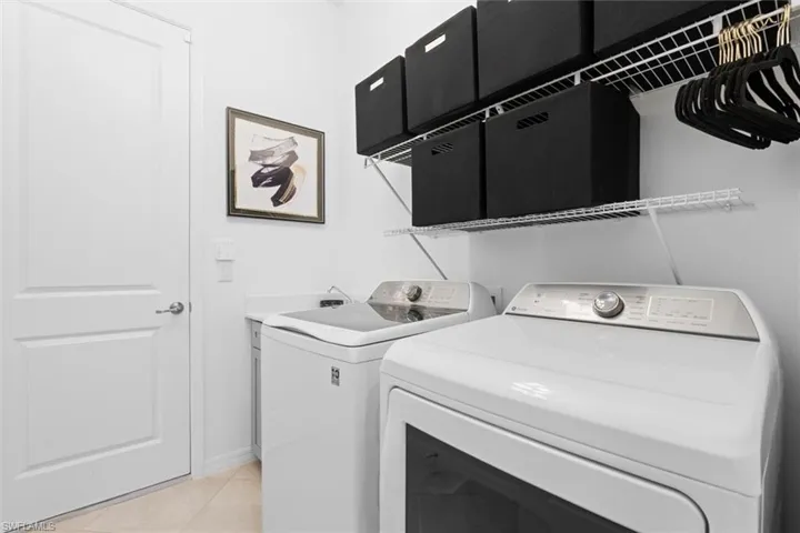 Laundry area featuring light tile floors and washing machine and clothes dryer