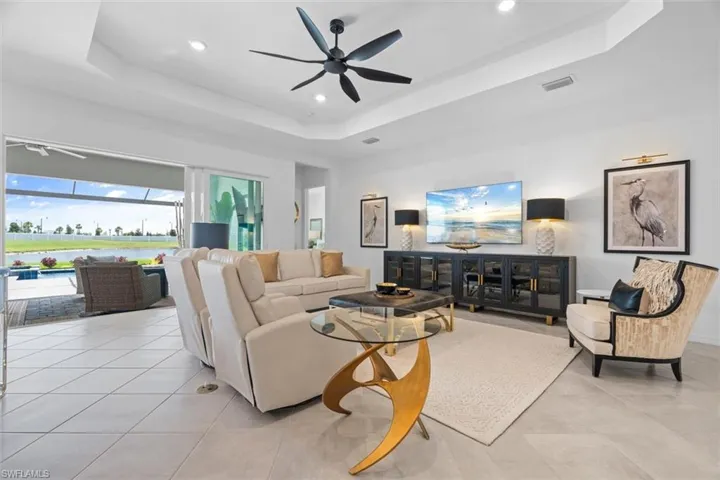 Tiled living room featuring ceiling fan and a tray ceiling
