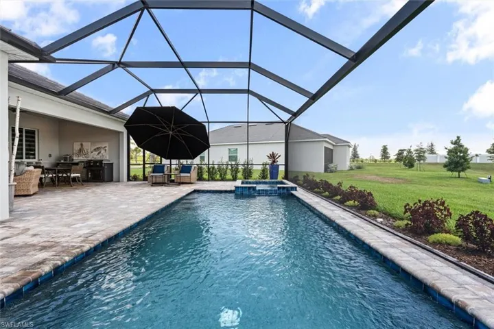 View of pool featuring a patio, a lanai, an in ground hot tub, and a lawn