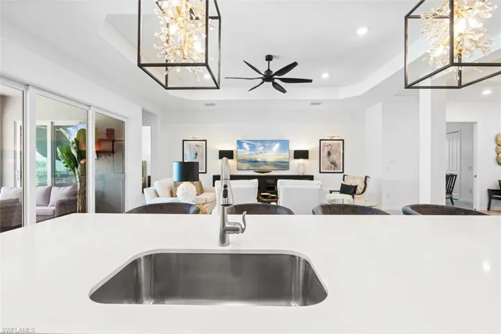 Kitchen with sink, a tray ceiling, and ceiling fan with notable chandelier
