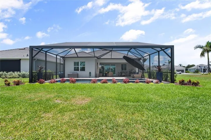 Back of property with glass enclosure and a yard