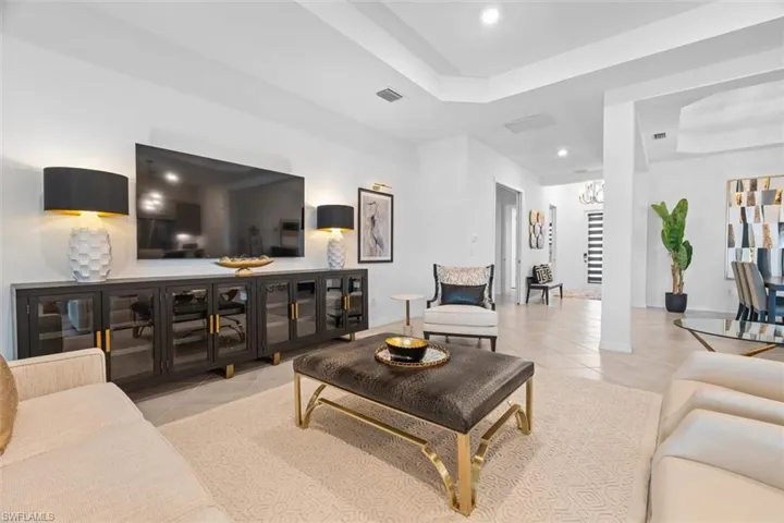 Tiled living room featuring an inviting chandelier and a tray ceiling