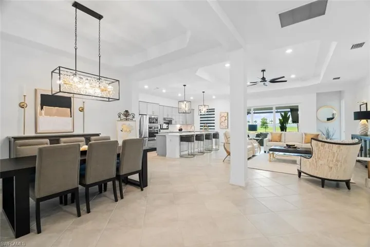 Tiled dining room featuring a raised ceiling and ceiling fan with notable chandelier