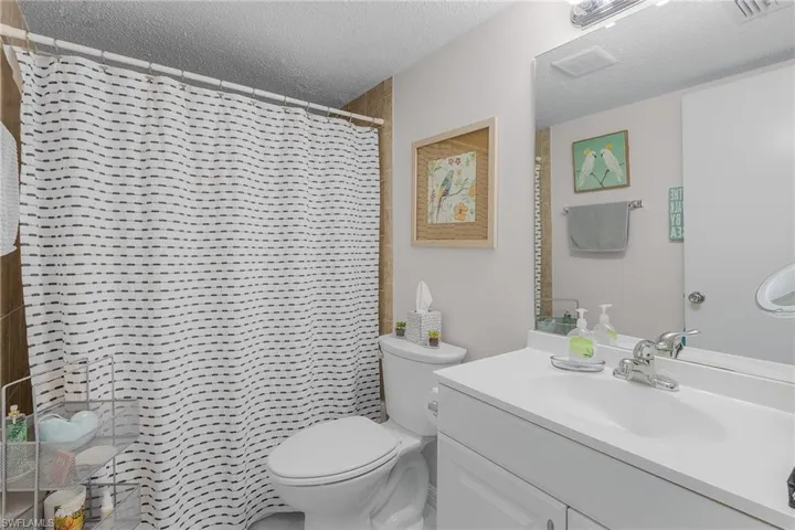 Bathroom with vanity, a textured ceiling, and a shower with curtain