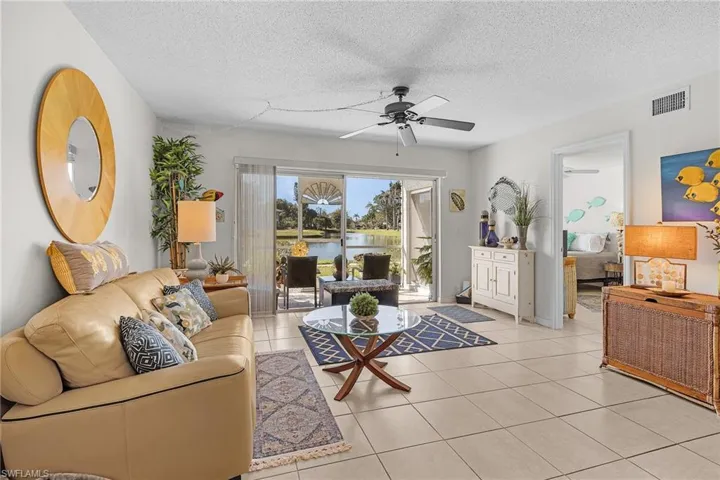 Living area with a textured ceiling, tile patterned floors, a water view, and a ceiling fan