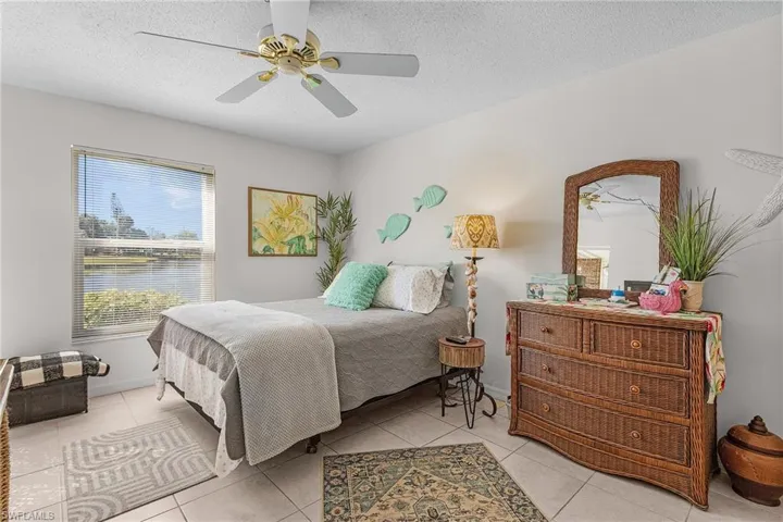 Bedroom with a textured ceiling, a ceiling fan, and light tile patterned floors