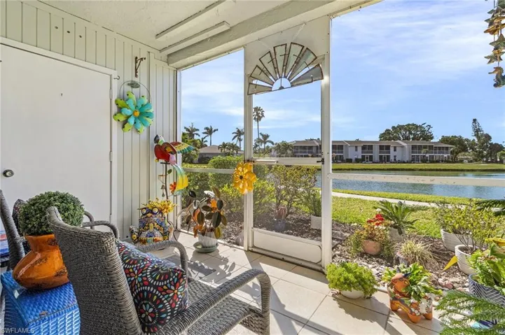 Sunroom / solarium with a water view, tile patterned flooring, and wood walls