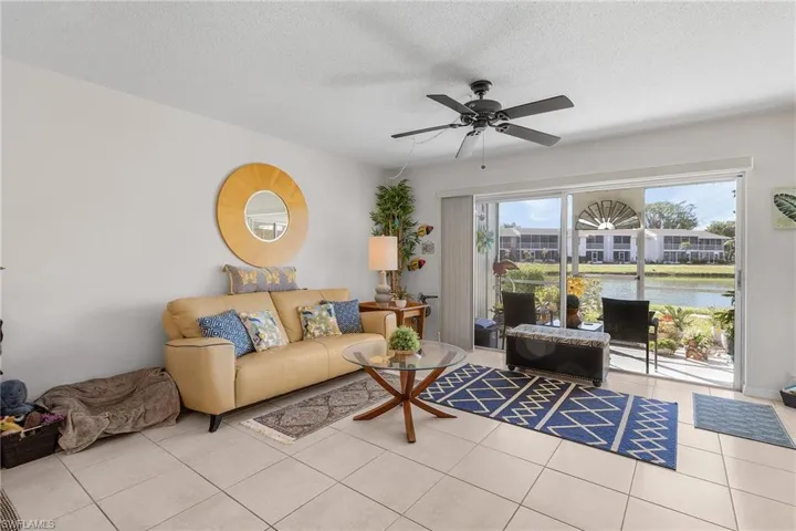 Tiled living room with a textured ceiling, a ceiling fan, and a water view