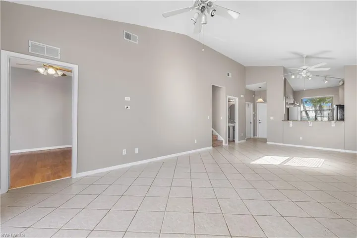 Unfurnished living room with ceiling fan, light tile patterned floors, and high vaulted ceiling
