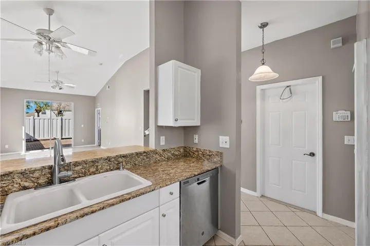 Kitchen with ceiling fan, sink, light tile patterned floors, dishwasher, and white cabinetry