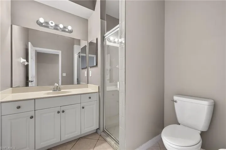 Ensuite Bathroom featuring tile patterned floors, vanity, an enclosed shower, and toilet