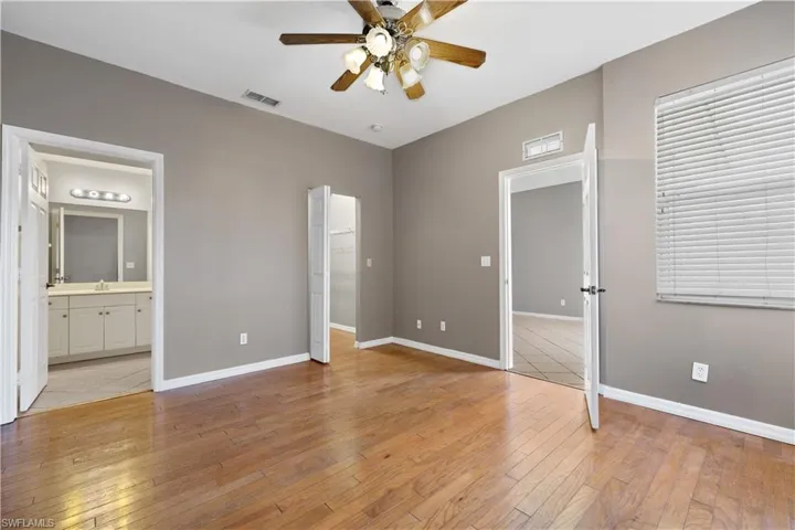 First floor Bedroom with ensuite bathroom, ceiling fan, sink, multiple windows, and light hardwood / wood-style floors