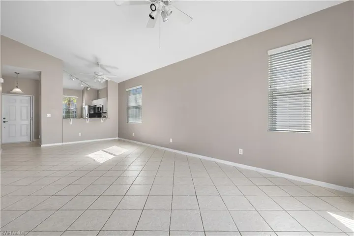 Tiled living room featuring ceiling fan and lofted ceiling