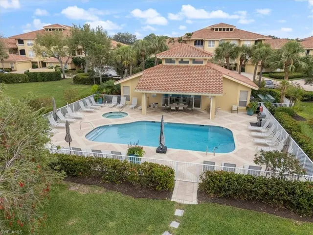 Community pool featuring a patio area, a fenced backyard, a community hot tub, and a lawn