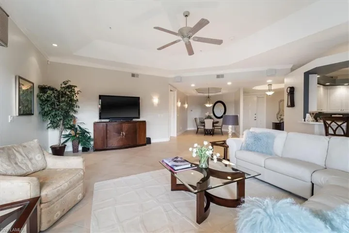 Living room with light tile patterned floors, ceiling fan, recessed lighting, visible vents, and a raised ceiling